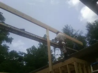 Carpenter setting a ridge beam over a new addition frame — Ice Dam Removal by Roofing Brothers in Six Mile