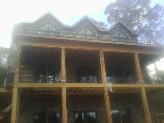 Dormers and porch framing on a large log home under construction — Roof Coating work by our crew in Six Mile