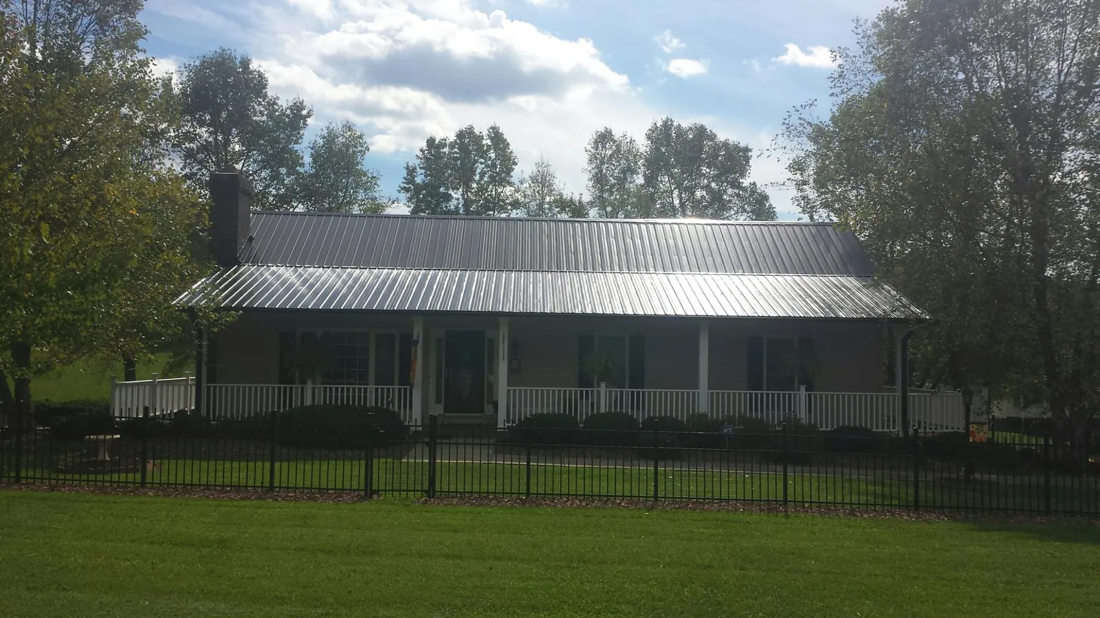 Gray metal roof on a brick ranch with a full width front porch — Gutter Guard Installation work by our crew in Six Mile