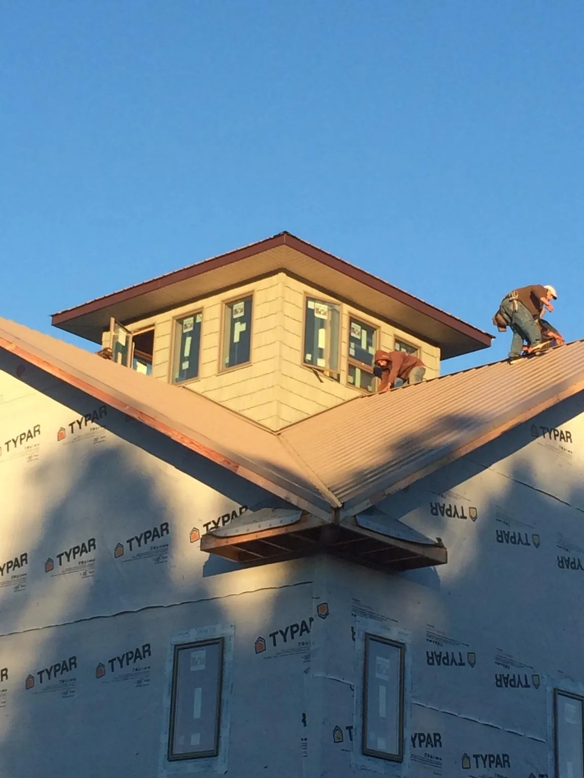 Roofers working around a rooftop cupola on a new metal roof at sunset — Roof Waterproofing in Six Mile by Roofing Brothers